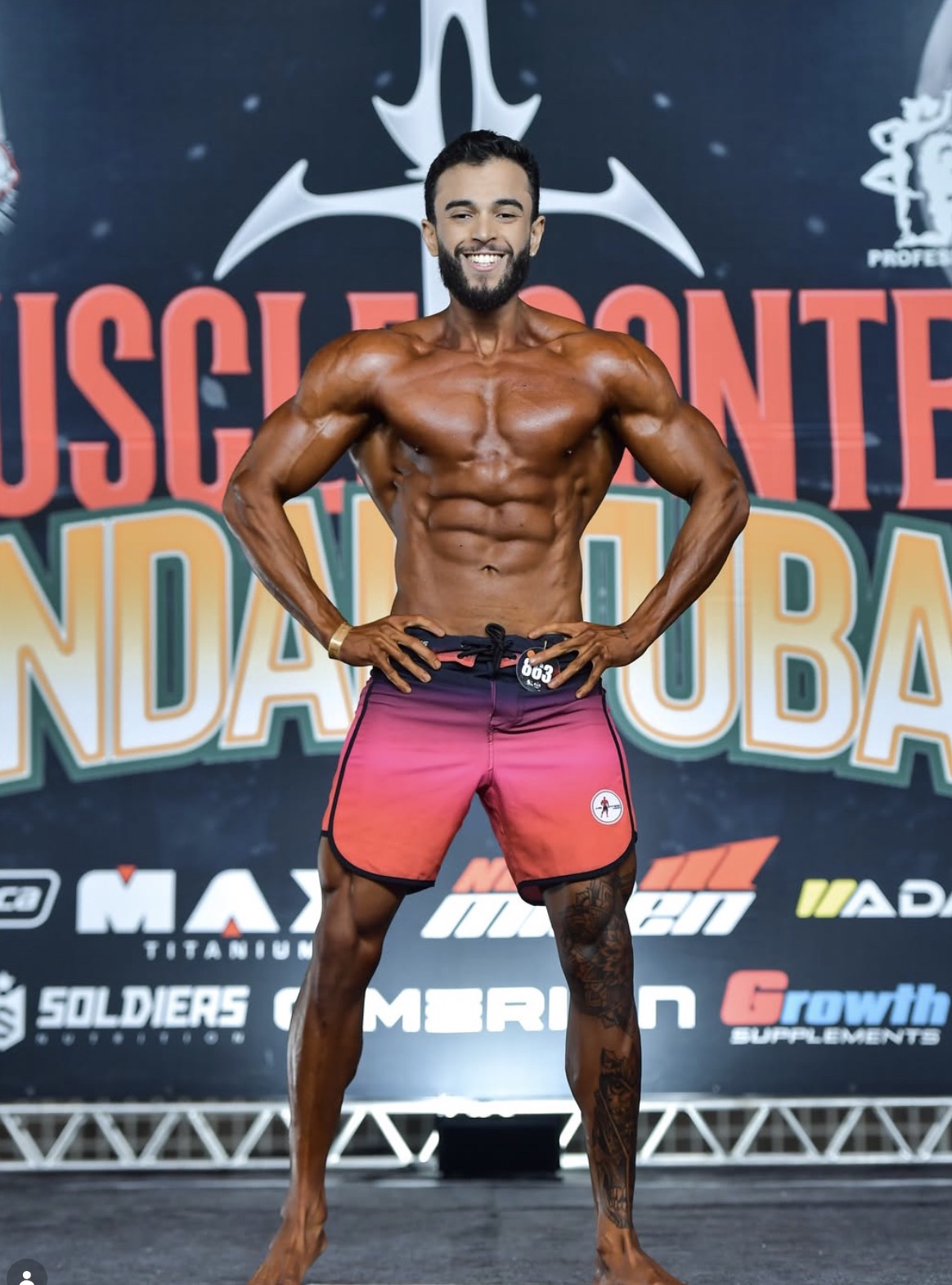 Coach Igor Vinicius em pose no palco de campeonato de Men's Physique